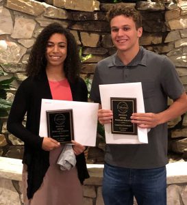 A senior girl and a senior boy hold award plaques