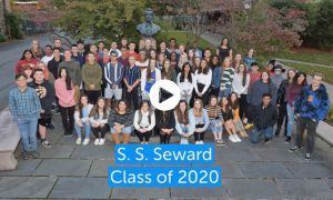 Image of the cover slide of a video slide presentation of the Class of 2020 recognition awards and scholarships. It shows the class posing in front to SS Seward's memorial.