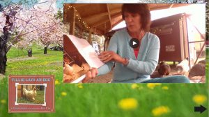 A farm background with grass and flowers and trees. In the center is a video of a woman with short brown hair and blue sweater reading a book.