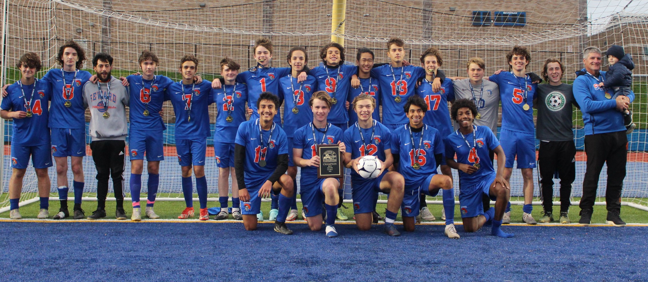 A group of high school soccer players full team wearing blue soccer uniformsholding a plaque