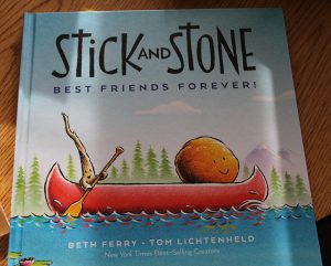 A book cover. Title is Stick and Stone Best Friends Forever! printed in thin black letters.  Under the title is an orange canoe on a blue lake. In the canoe is a stone with a face in the front and a stick in the back paddling. Beth Ferry Tom Lichtenheld