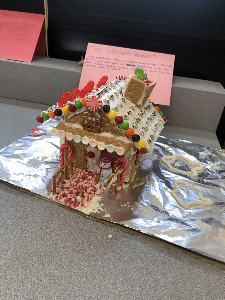 The winning gingerbread house has lots of colorful candies along the roof, a chimney, a snowman on the porch.