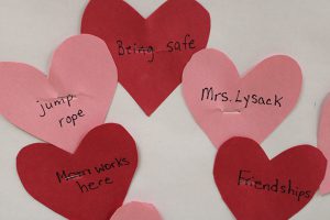 A few red and pink hearts with messages of what the children love: Mrs. Lysack, friends, my mom works here, being safe and jump rope.