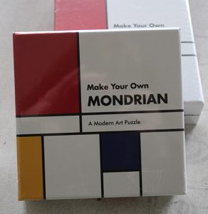 A puzzle box with black lines and rectangles in red, yellow and blue. It says Make Your Own Mondrian 