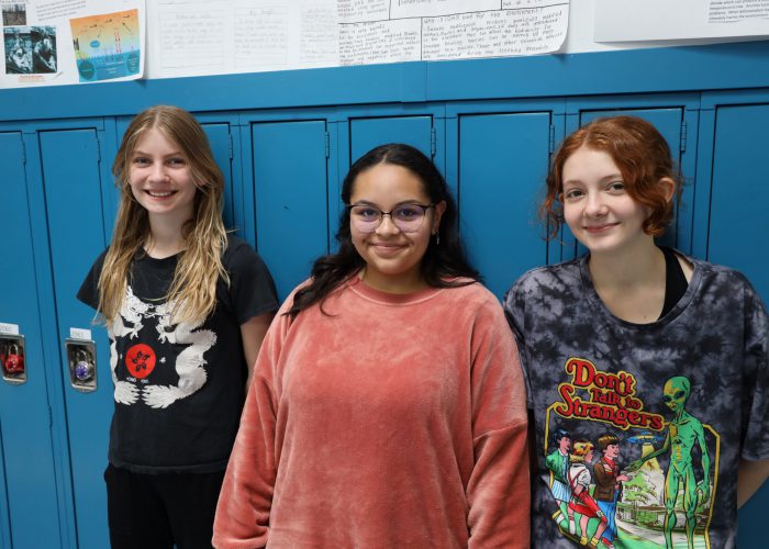 Three students pose near lockers