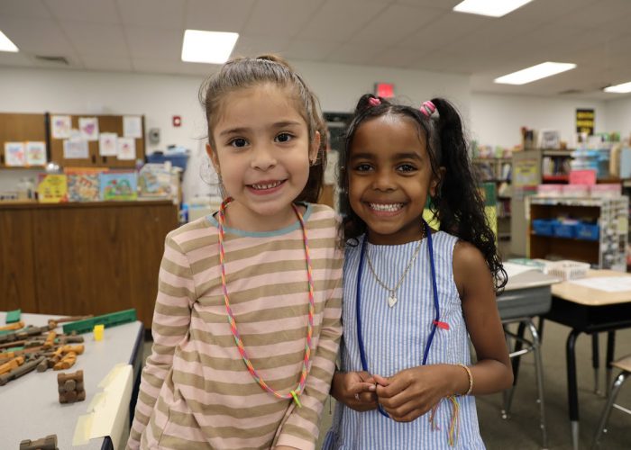 Two students pose for a photo in a classroom