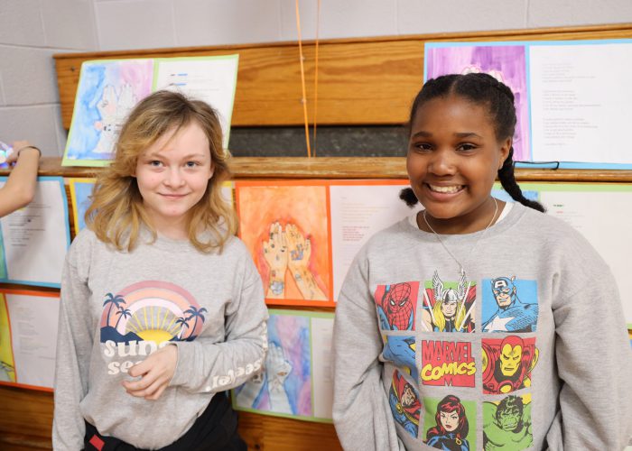 Two students pose in front of art work