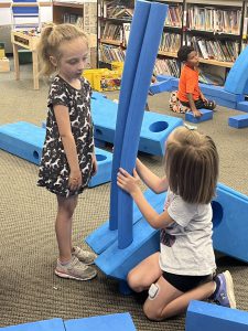 Two students work to put a blue structure together