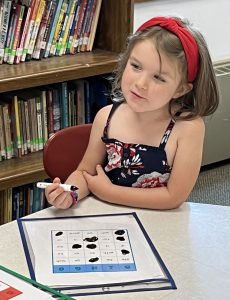 A student pauses while working on paper with a black marker