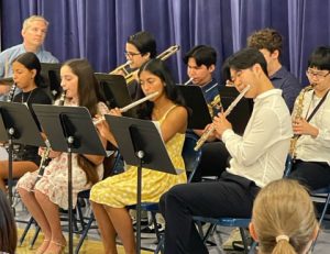 Band members play their instruments in front of a blue curtain