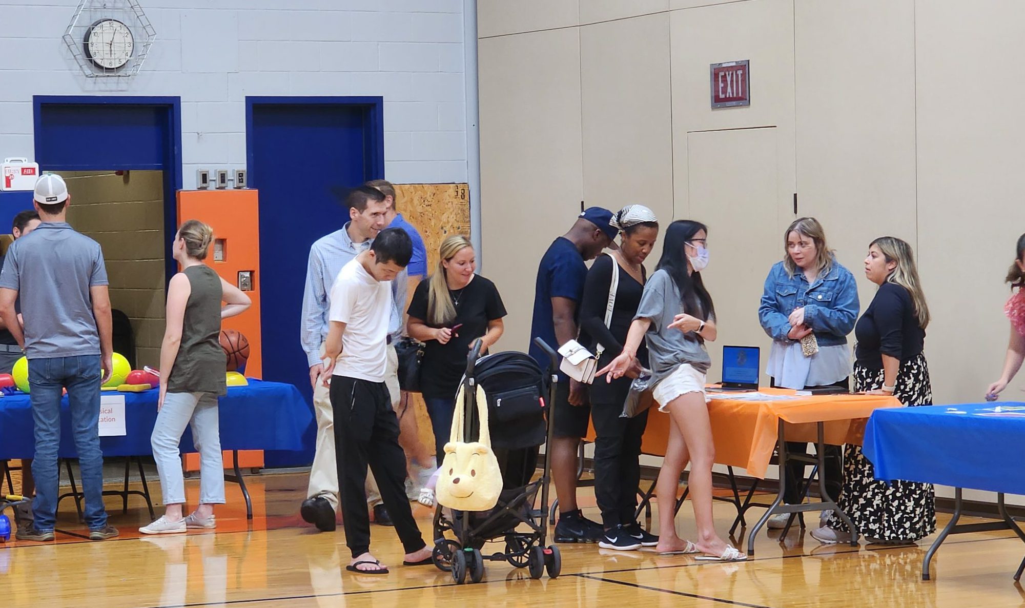 People look at information tables set up in a gymnasium