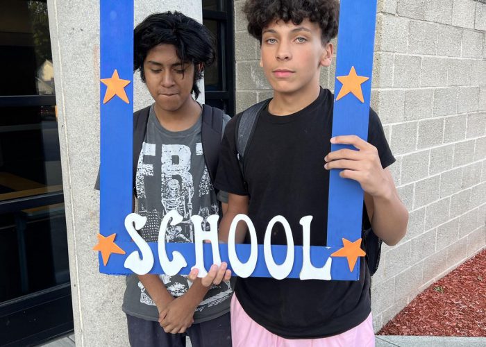 Two students pose with a first day of school frame