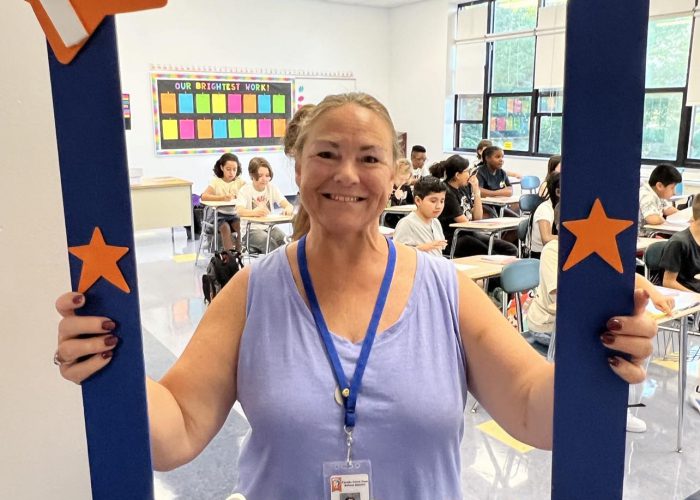 A person poses with a first day of school frame