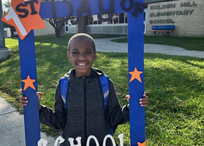 A student holds a first day of school frame