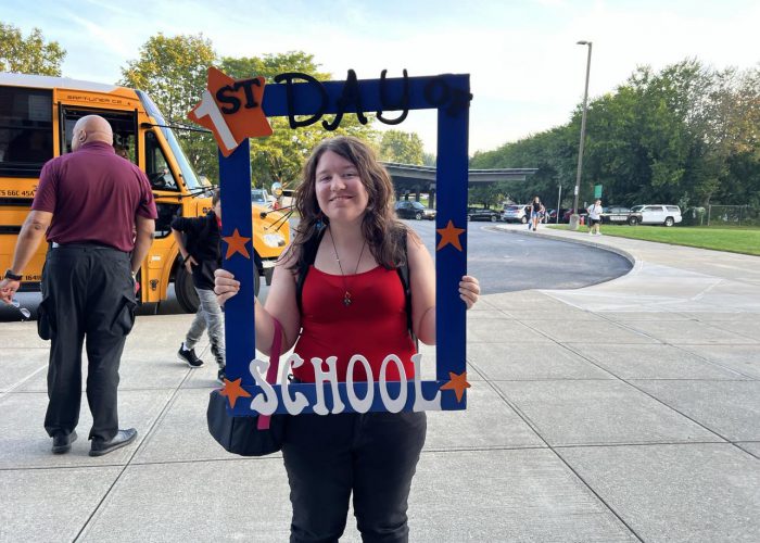 A student poses with a first day of school frame