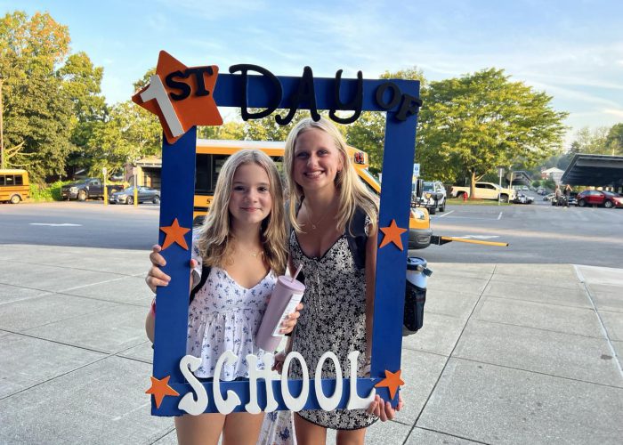 Two students pose with a first day of school frame