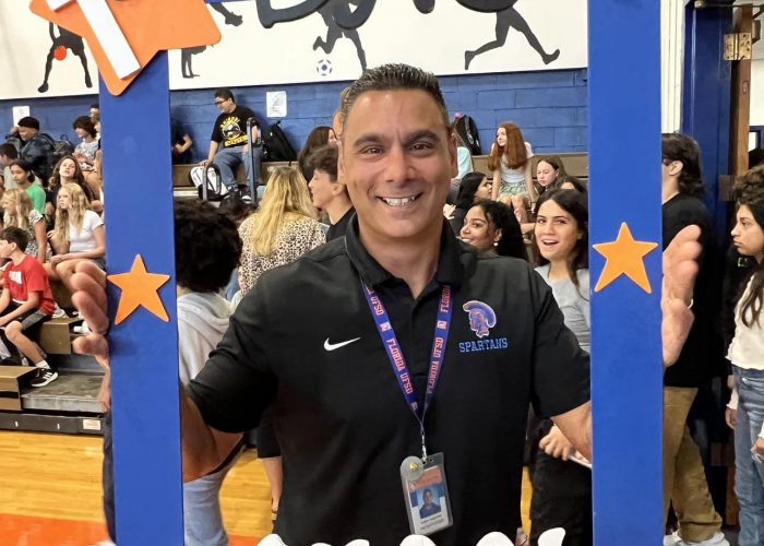 A person poses with a first day of school frame