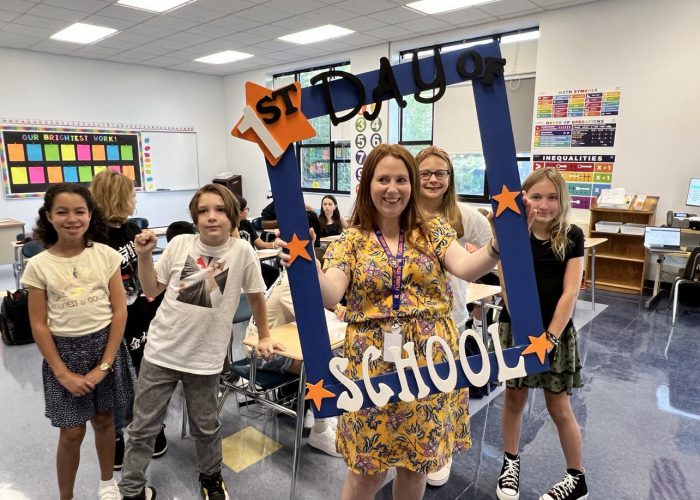 A group poses with a first day of school frame