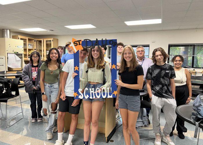 A group poses with a first day of school frame