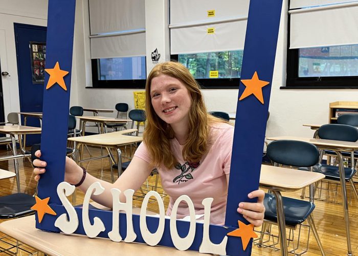 A person poses with a first day of school frame