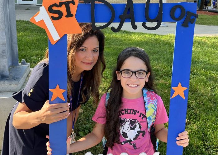 An adult and child hold a First day of school frame