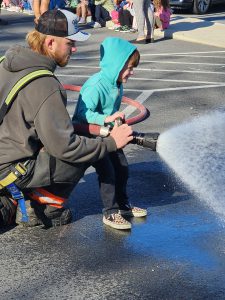 Golden Hill Elementary Student spraying hose from fire truck