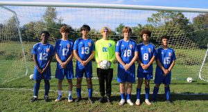 Seven soccer players pose for a photo in front of a goal