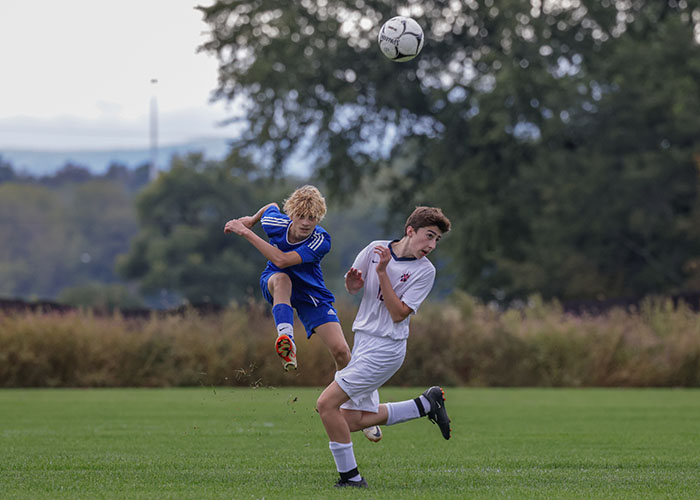 Two soccer players go for the ball