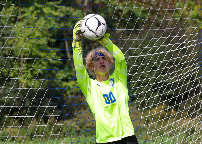 A goalie in yellow catches the ball