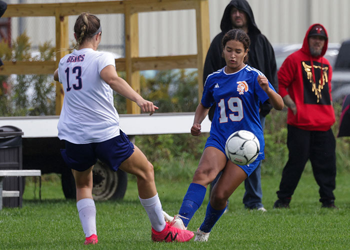 Two soccer players compete for the ball