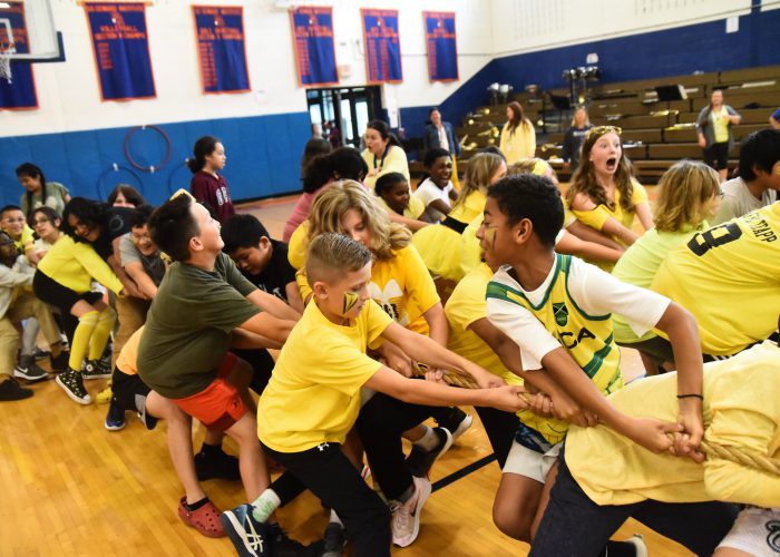 Group of students in yellow pulling on a rope for tug of war at pep rally