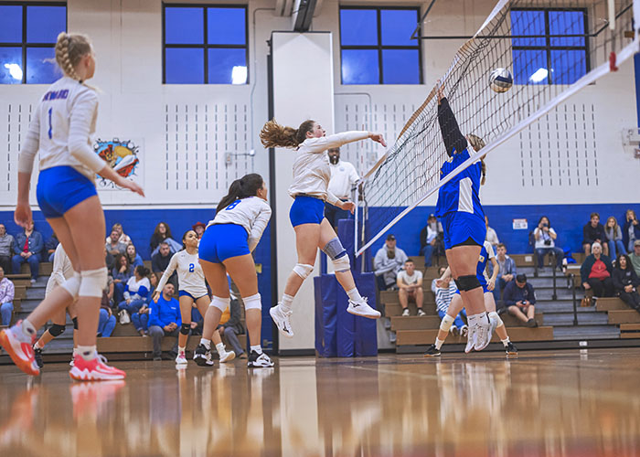 A player hits the ball over the net as another player attempts to defend