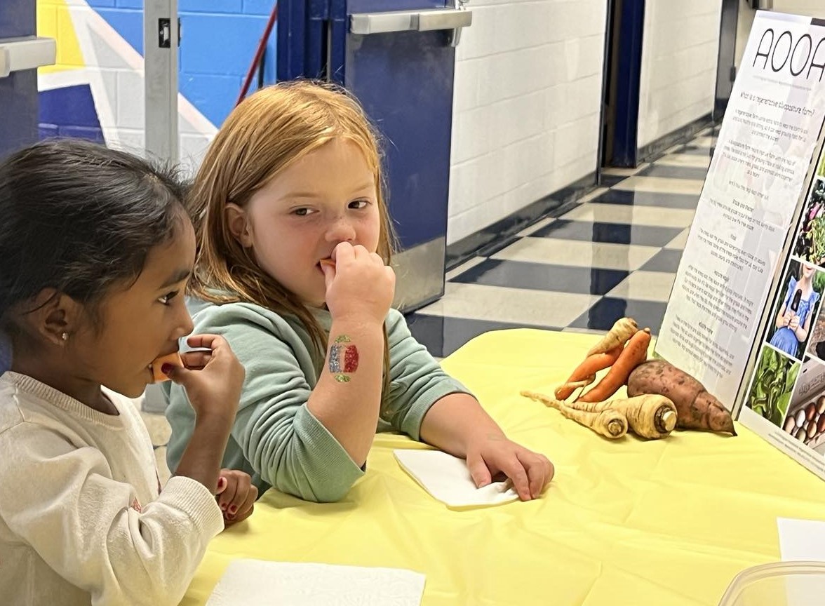 Two students try a bite of food while sitting at a table