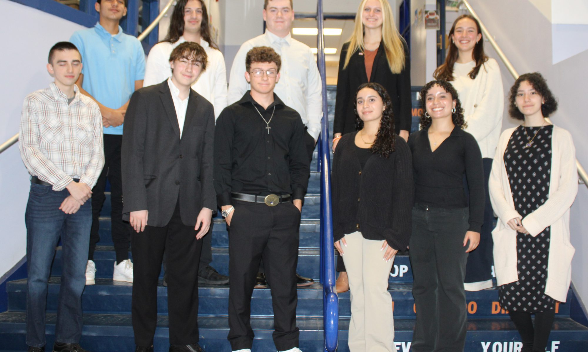 11 students pose on a set of blue stairs