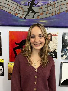 Student posing in front of posters