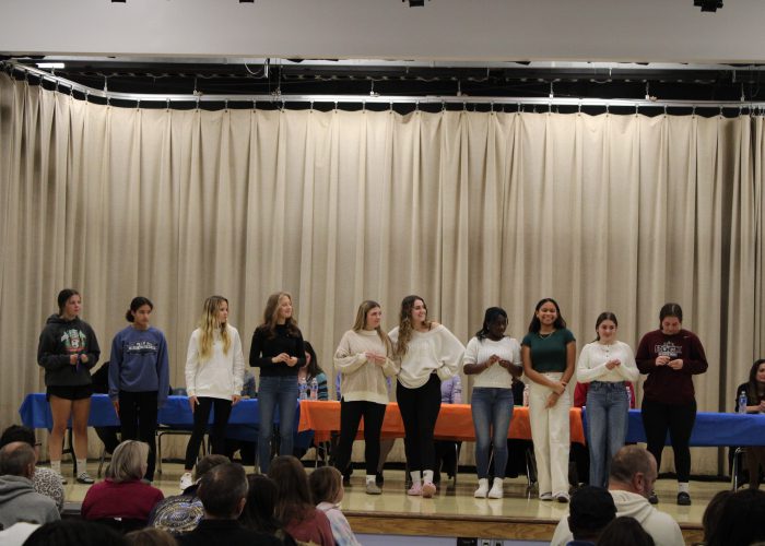 Student athletes pose on stage for a photo