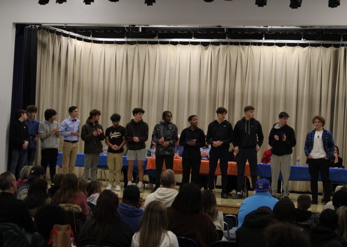 Student athletes pose on stage for a photo