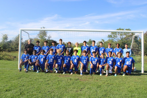 Team of soccer players wearing blue uniforms posing for photo