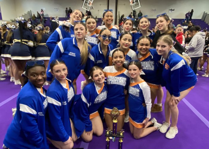 Cheerleading team pose for photo with trophy