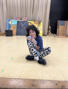 Student sitting on stage with black and white pants