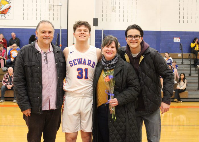 Family poses with student-athlete in gymnasium