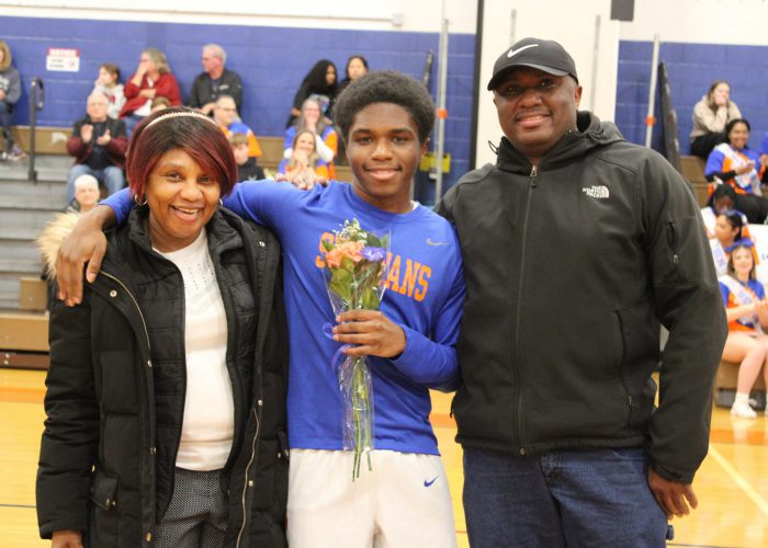 Family poses with student-athlete in gymnasium