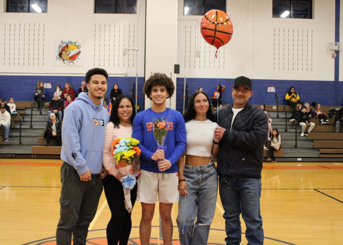 Family poses with student-athlete in gymnasium