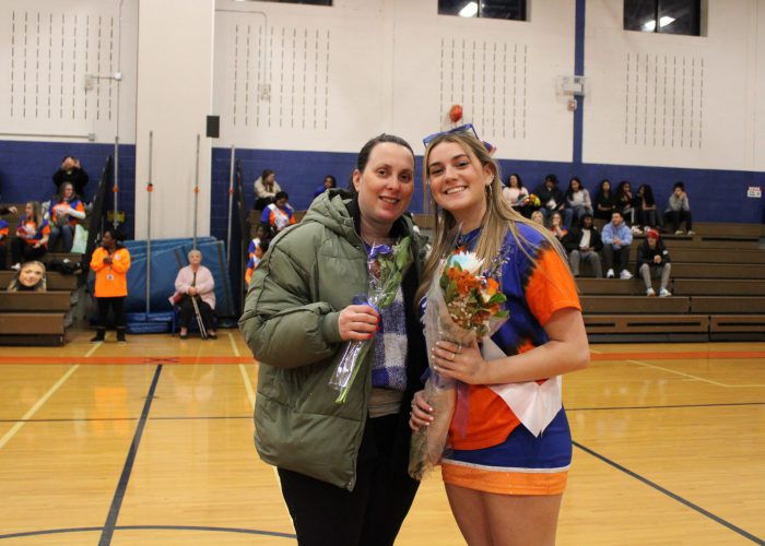 Family poses with student-athlete in gymnasium