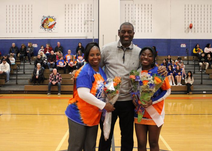 Family poses with student-athlete in gymnasium