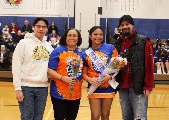 Family poses with student-athlete in gymnasium