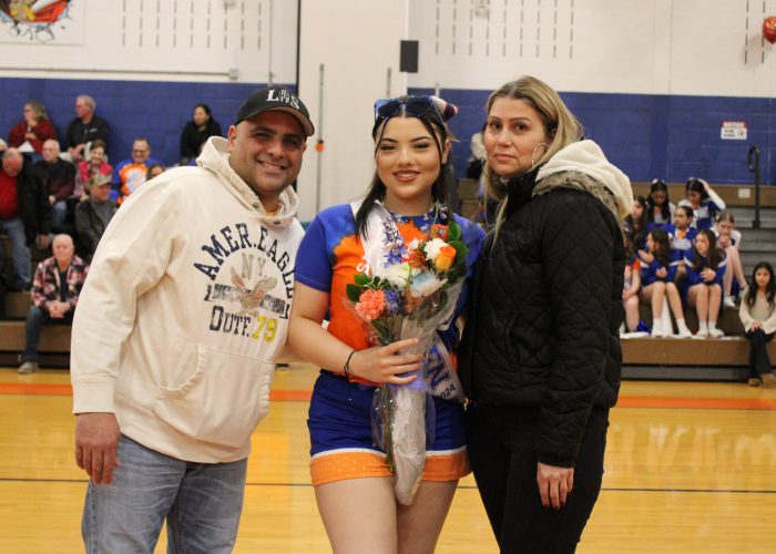 Family poses with student-athlete in gymnasium