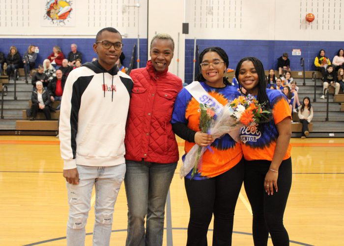 Family poses with student-athlete in gymnasium