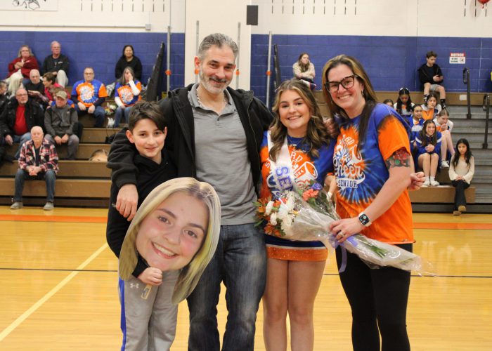 Family poses with student-athlete in gymnasium