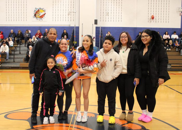 Family poses with student-athlete in gymnasium